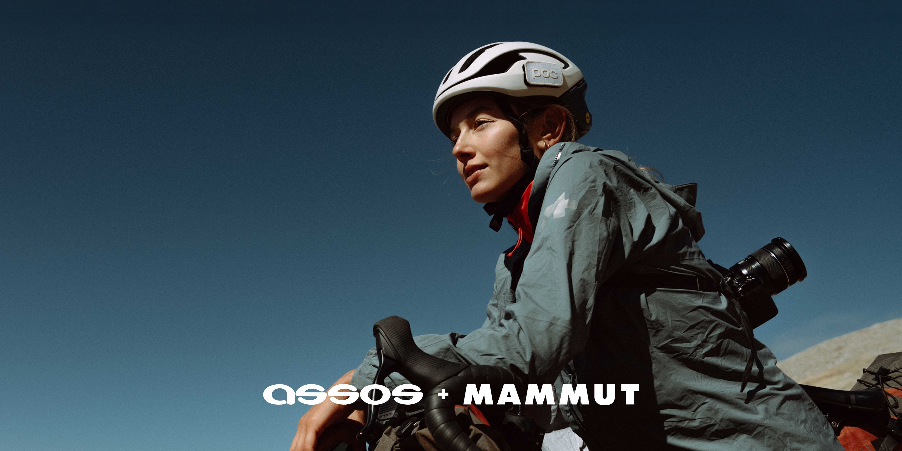 Cyclist in Mammut outdoor gear rides under a clear blue sky, with "assos + MAMMUT" text overlay.